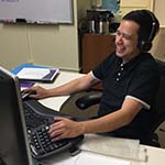 image of Alex Ruiz with a headset and typing on a computer