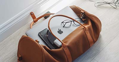leather bag with computer and glasses on top