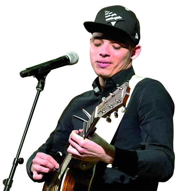 Anthony Ramos playing the guitar in front of a microphone