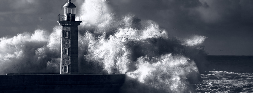 A lighthouse against a stormy night with crashing waves