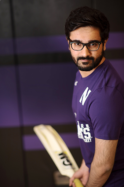 Ali in uniform, holding a cricket bat